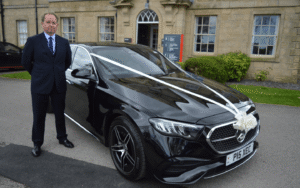 chauffeur with mercedes-benz e class, complete with wedding bow decorations.