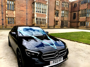 black mercedes-benz wedding car with blue ribbon to match bride and grooms wedding theme at Temple Newsam in Leeds