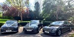 three wedding cars decorated with ribbon to match theme of wedding. S class and two E class mercedes benz black saloons